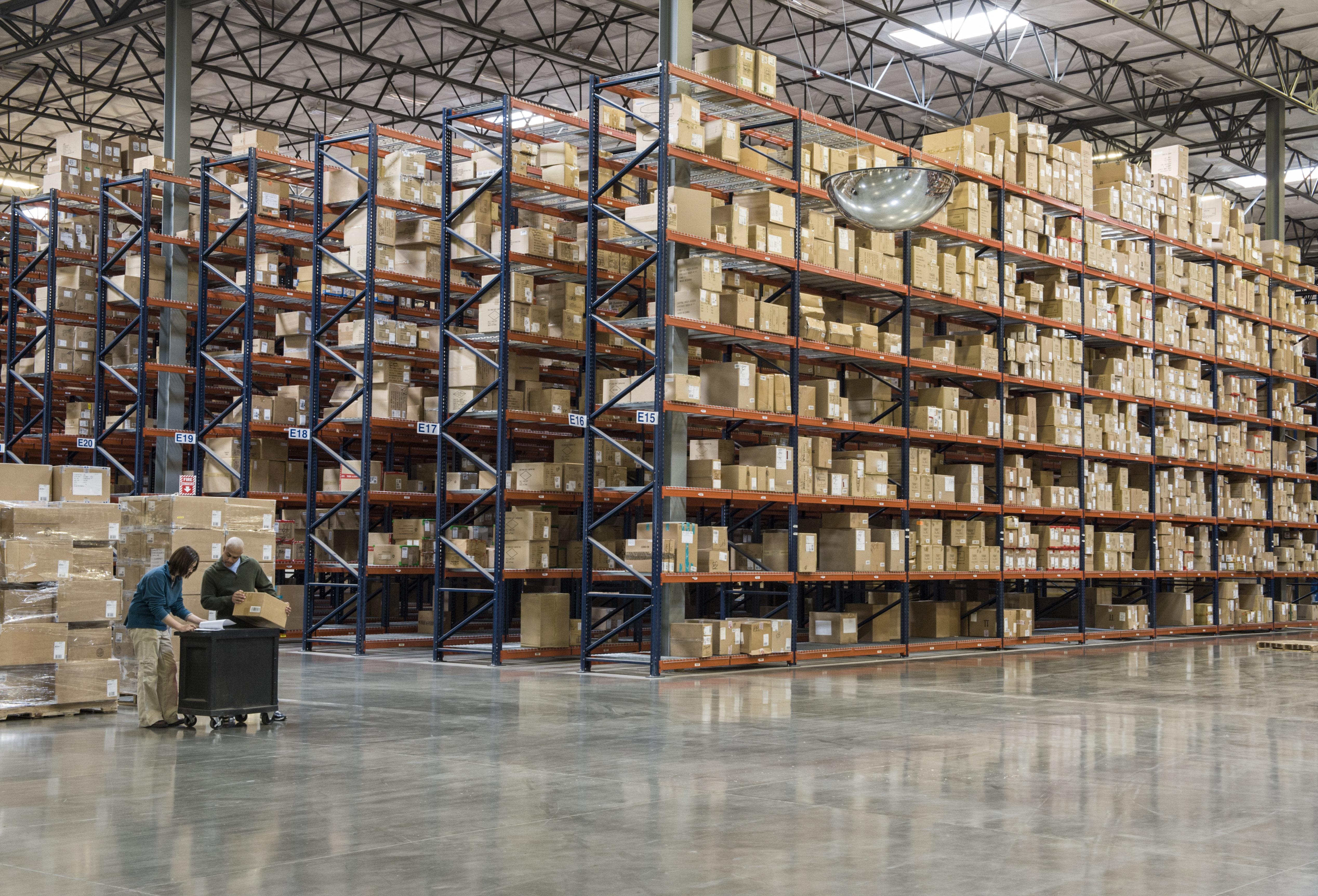 Two employees checking inventory in temporary storage in a distribution warehouse. Two employees checking inventory in temporary storage in a distribution warehouse.